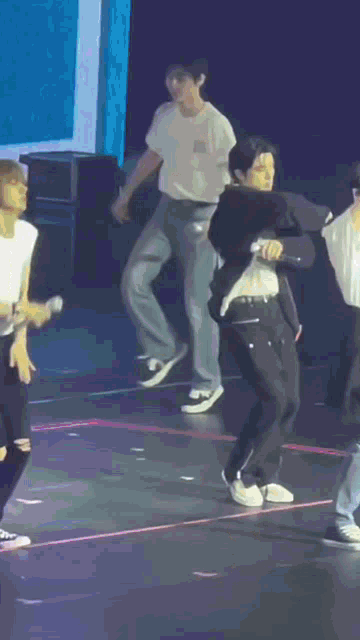 a man in a suit is dancing on a stage with other people .