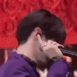 a man in a purple shirt is holding a microphone in his hand .
