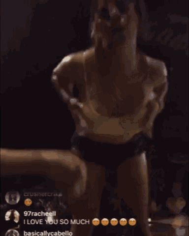 a woman in a yellow top and black shorts is dancing in front of a dark background