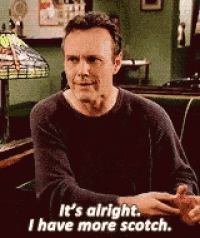 a man is sitting at a table and says it 's alright . i have more scotch .