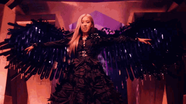 a woman in a black dress with wings on her arms