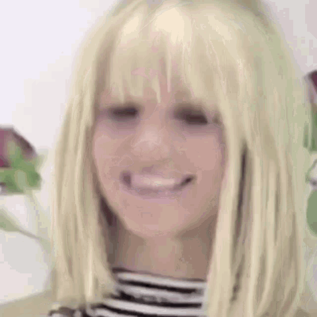 a close up of a woman wearing a blonde wig and smiling .