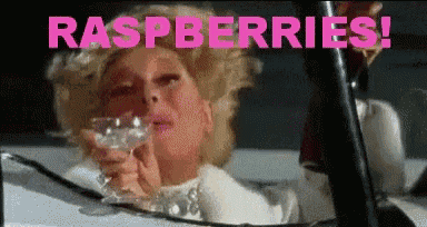 a woman is holding a glass of wine and the words raspberries are above her head