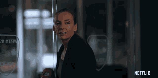 a woman stands in front of a glass door that says netflix on the bottom