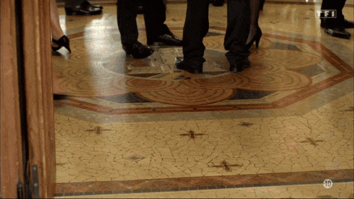a group of people standing on a tiled floor with the number 10 on the bottom right corner