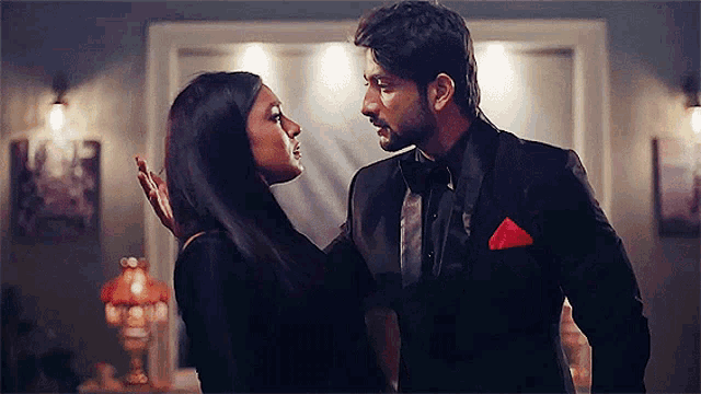 a man and a woman are standing next to each other and looking at each other in a room .