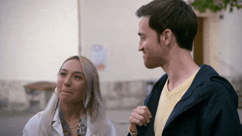 a man and a woman are standing next to each other and the man is wearing a blue jacket