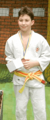 a young boy in a white karate uniform is holding a medal
