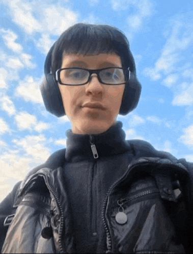 a man wearing headphones and glasses looks at the camera
