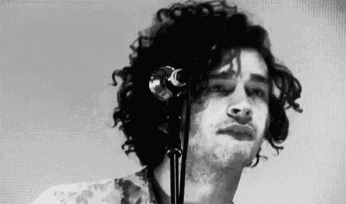 a black and white photo of a man singing into a microphone .
