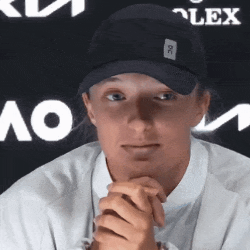 a woman wearing a black hat and a white shirt with a lex logo behind her