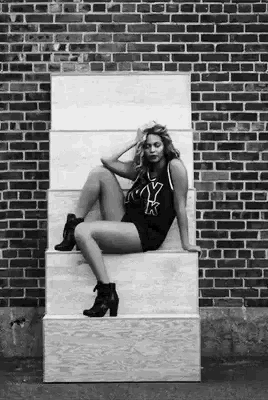 a black and white photo of a woman sitting on a set of stairs .