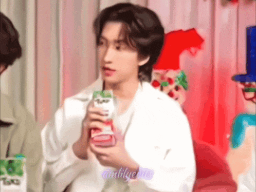 a young man in a white jacket is holding a bottle of milk .