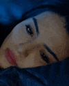 a close up of a woman laying in bed with her head on a pillow .