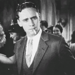 a man in a suit and tie is smoking a cigarette in a black and white photo