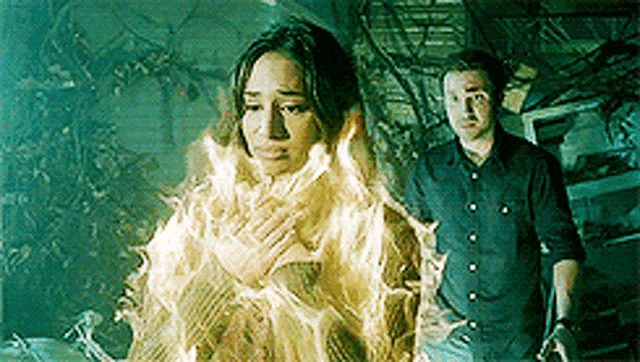 a man and a woman are standing next to each other . the woman is on fire and the man is standing behind her .