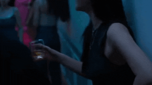 two women are kissing in a dark room .