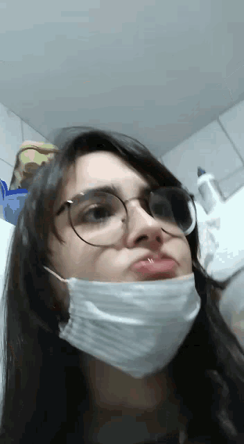 a woman wearing a mask and glasses is making a face .