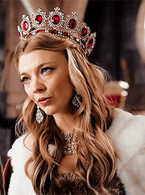 a woman wearing a crown and earrings is sitting in a chair