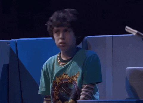 a young boy wearing a green t-shirt with a picture of a planet on it