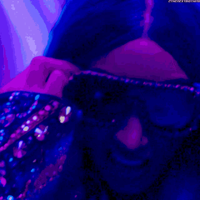 a woman with blue hair is wearing sunglasses and a purple background