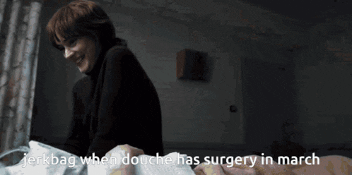 a woman in a black turtleneck is smiling while looking at a man in a hospital bed ..