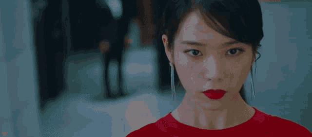 a close up of a woman wearing a red dress and red lipstick looking at the camera .