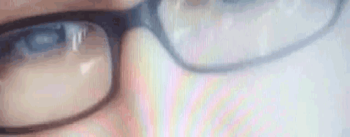 a close up of a person wearing glasses and looking at a computer screen .
