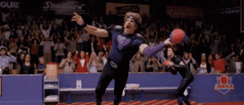 a man is jumping in the air while holding a ball in front of a crowd of people .