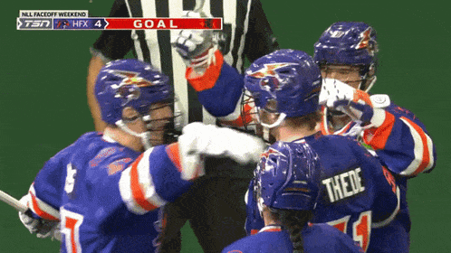 a group of hockey players celebrate a goal with a referee in the background