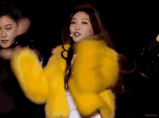 a woman is wearing a yellow fur coat and looking at the camera