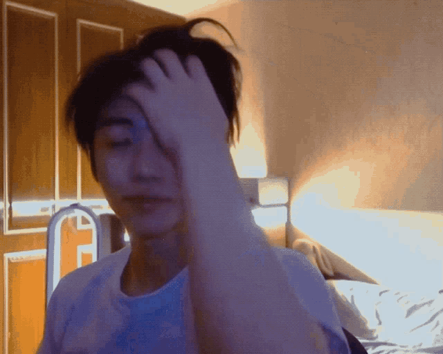 a man holds his hand to his forehead in a room