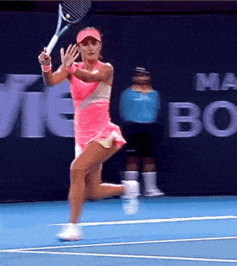 a woman in a pink dress is swinging a tennis racket