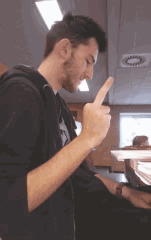 a man in a black hoodie is pointing his finger