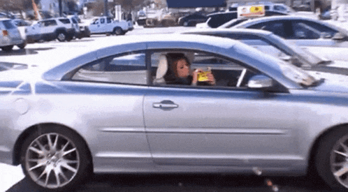 a woman sits in a car eating a snack