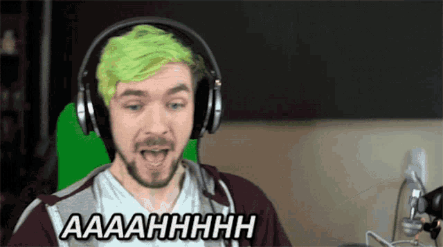a man with green hair is wearing headphones and says " aaaahhhhh "
