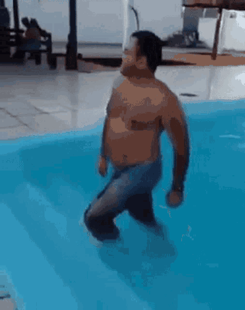 a man without a shirt is standing in a swimming pool .