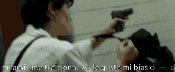 a man in a white shirt is pointing a gun at someone with the words " mi amix me traiciona " below him