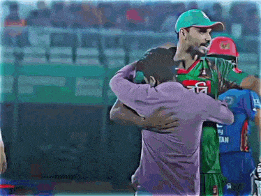 a man in a purple shirt is hugging a man in a green and red jersey that says tan