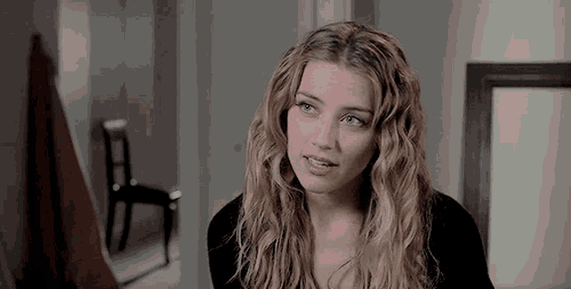 a woman with long blonde hair is looking at the camera