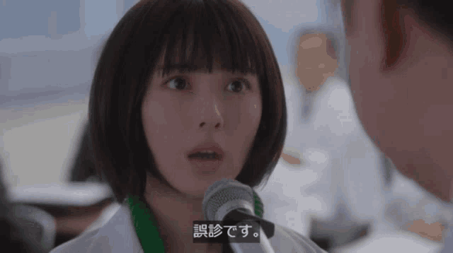 a woman speaking into a microphone with a green ribbon around her neck that says ' consultation '