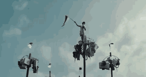 a person is standing on a pole holding a flag and a sign that says meeerr deee kaaa !!!
