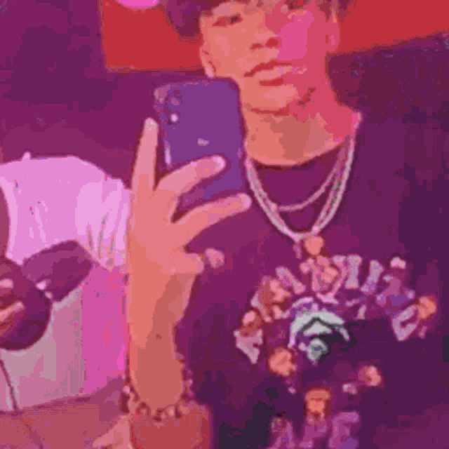 a man is taking a selfie with his cell phone in a purple room .