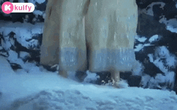 a woman in a white dress is walking through a snowy forest .