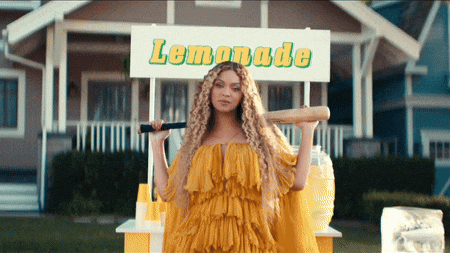 a woman stands in front of a lemonade stand holding a baseball bat