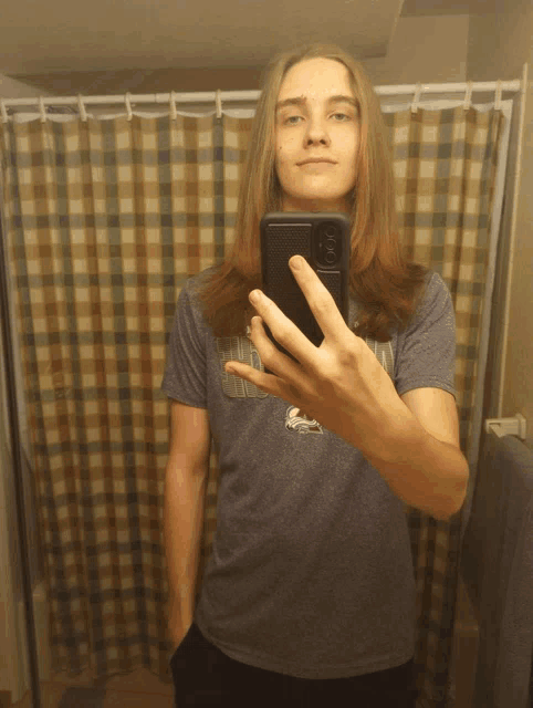 a young man takes a selfie in front of a shower curtain
