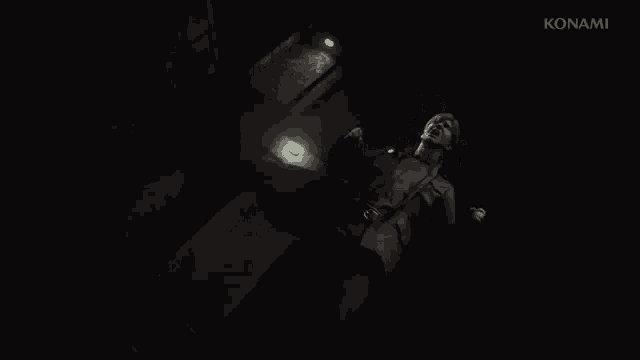 a man is laying on the ground in a dark room with his hands in the air .