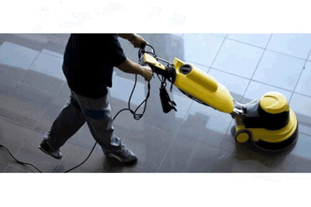 a man is using a yellow machine on a tile floor
