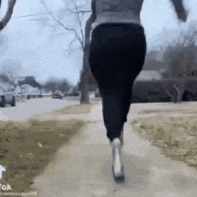 a woman is running down a sidewalk with a dog in her arms .