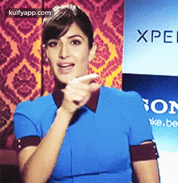 a woman in a blue shirt stands in front of a sony sign